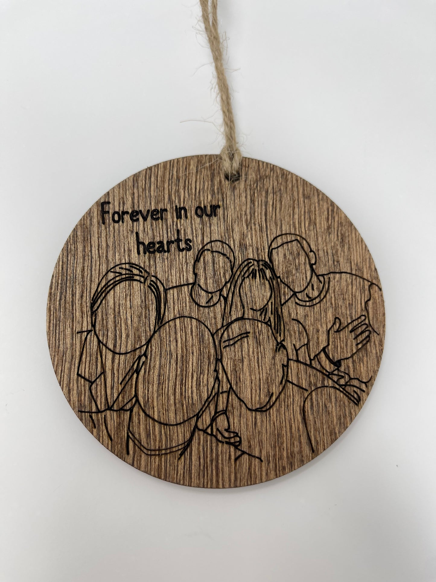 Wooden circular ornament with engraved design and 'Forever in our hearts' text on a white background