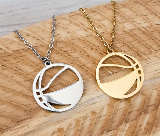 Two necklaces with circular pendants on a wooden surface