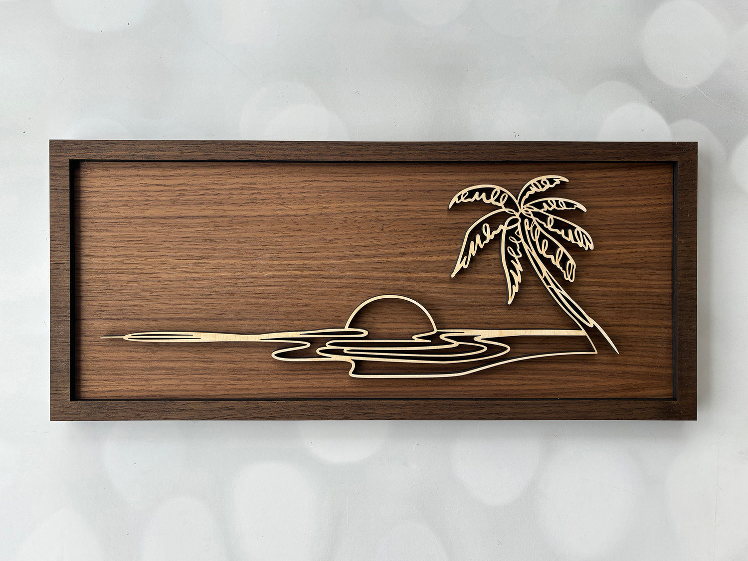 Wooden wall art with a palm tree design on a textured white background