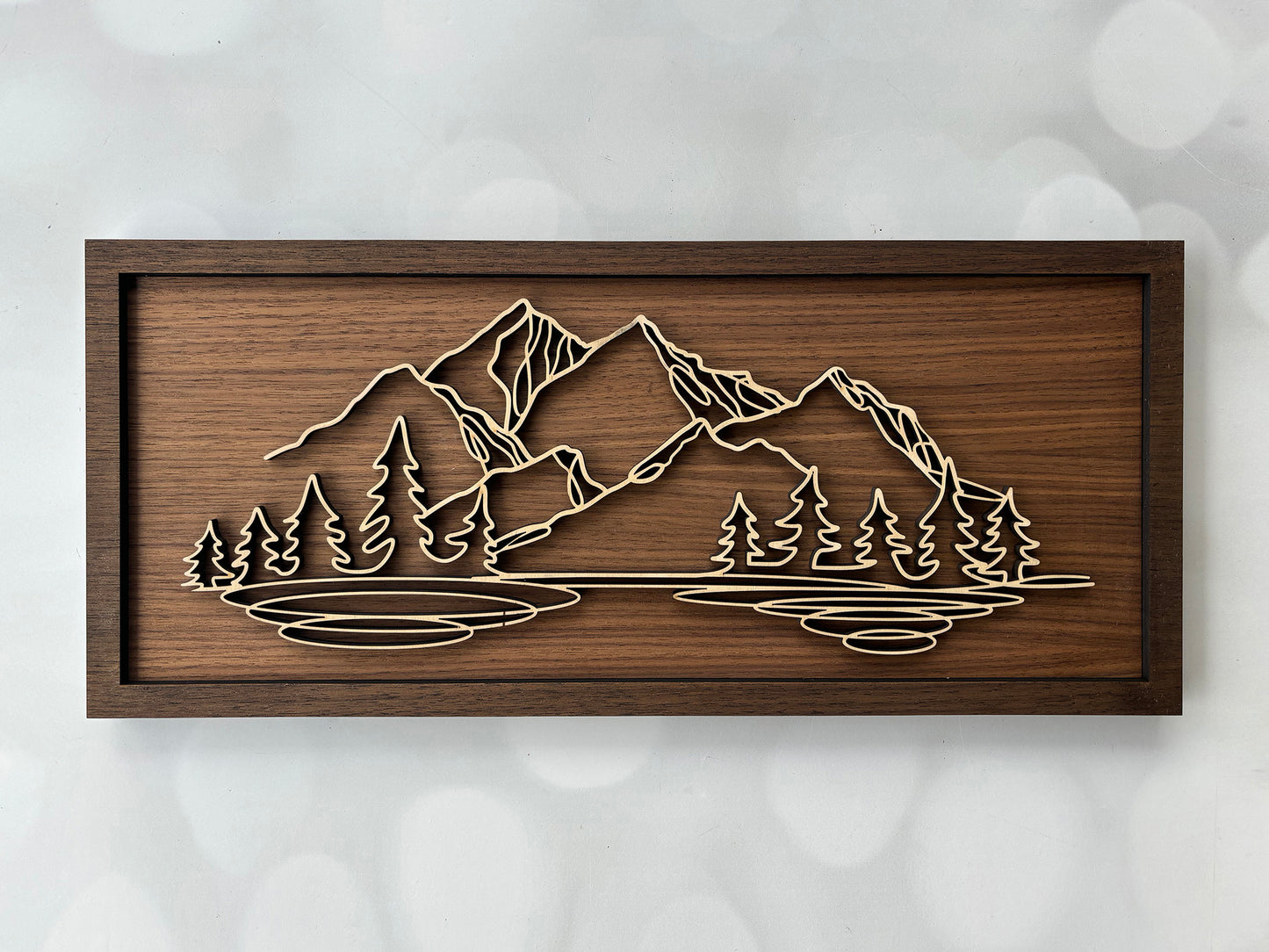Wooden wall art with mountain and tree design on a textured white background